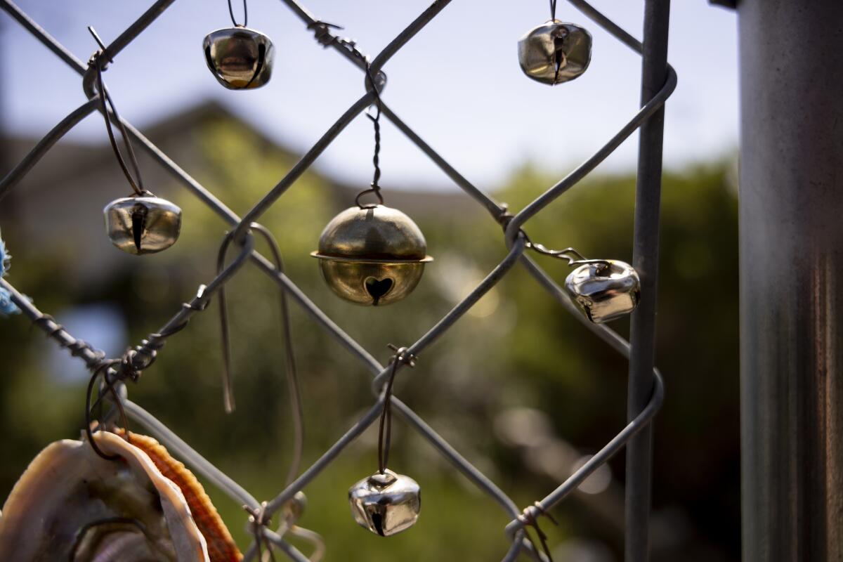 Small bells and oyster shells hang from chain link fencing at 7th Ave Garden 