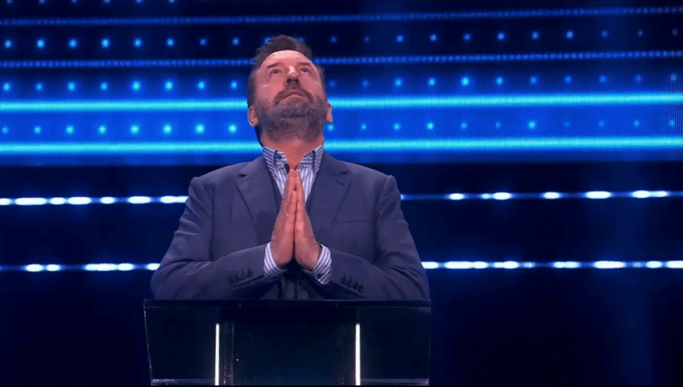 Man in suit praying at a podium.