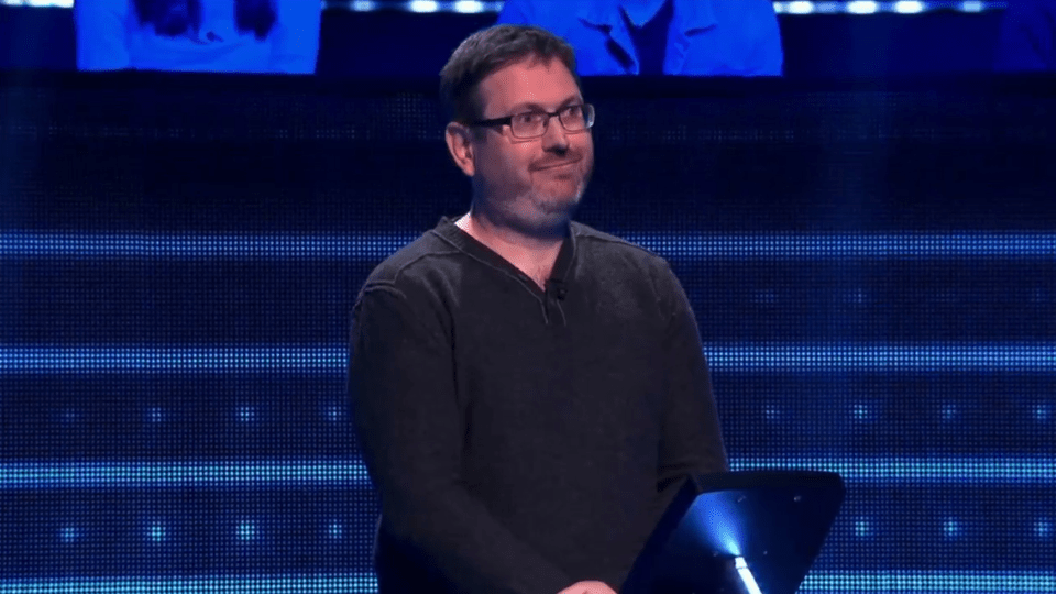 Man smiling in front of a blue screen.