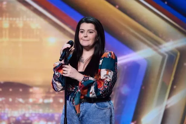 Louise Hall in a black top, floral shirt and blue jeans on the Britain's Got Talent stage with a microphone in an audition.