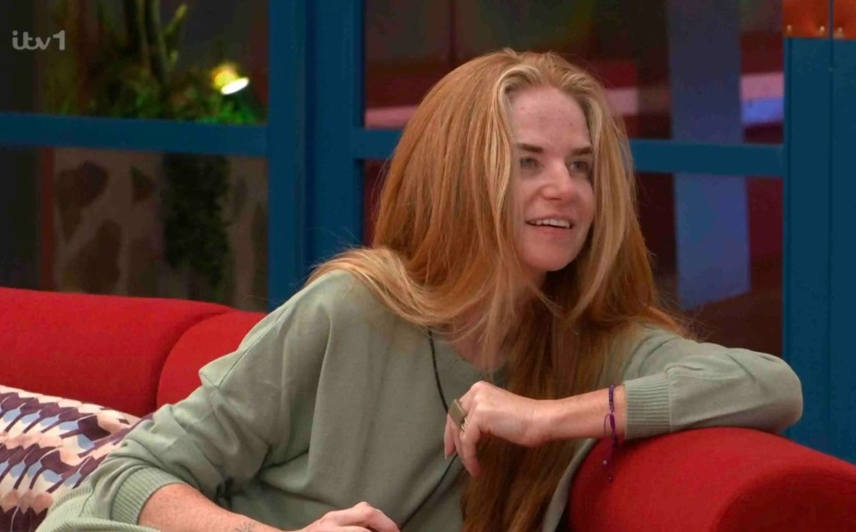 A woman with long blonde hair sits on a red couch.