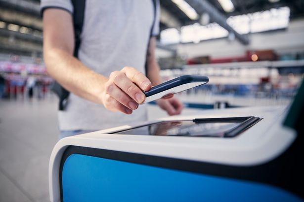 Passenger scanning ticket on smart phone at airport terminal.