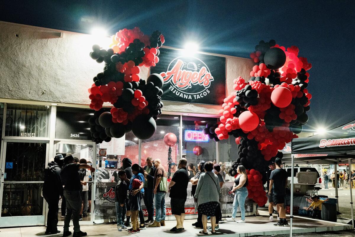Guests line up outside of Angel's Tijuana Tacos bricks-and-mortar in Anaheim. Red and black baloons decorate the exterior.