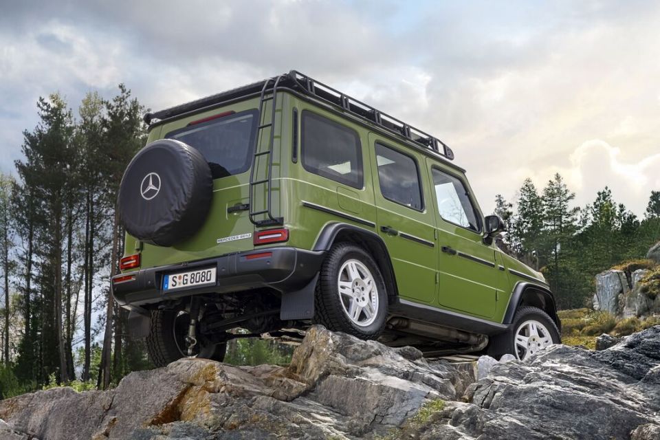 Green Mercedes G-Wagon driving over rocks.
