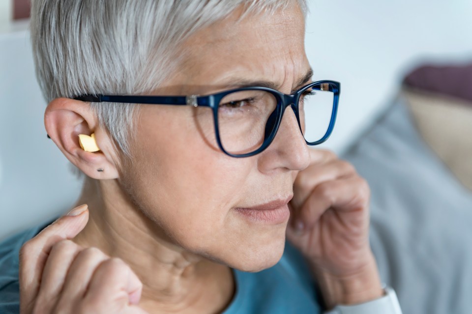 A mature woman inserting earplugs.