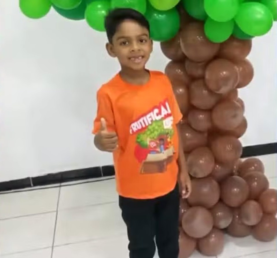 Boy giving thumbs up in front of balloon tree.