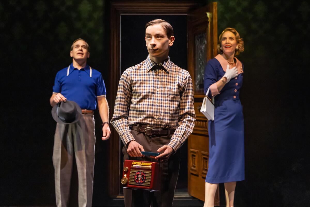 A boy clutching a radio stands with this parents in the stage play "Stranger Things: The First Shadow."
