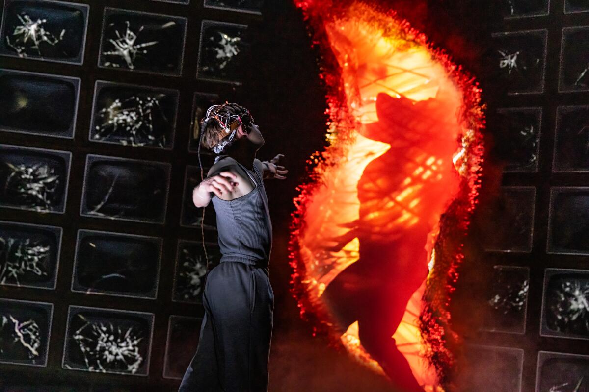 A figure appears in a fiery opening in a wall before a young man
