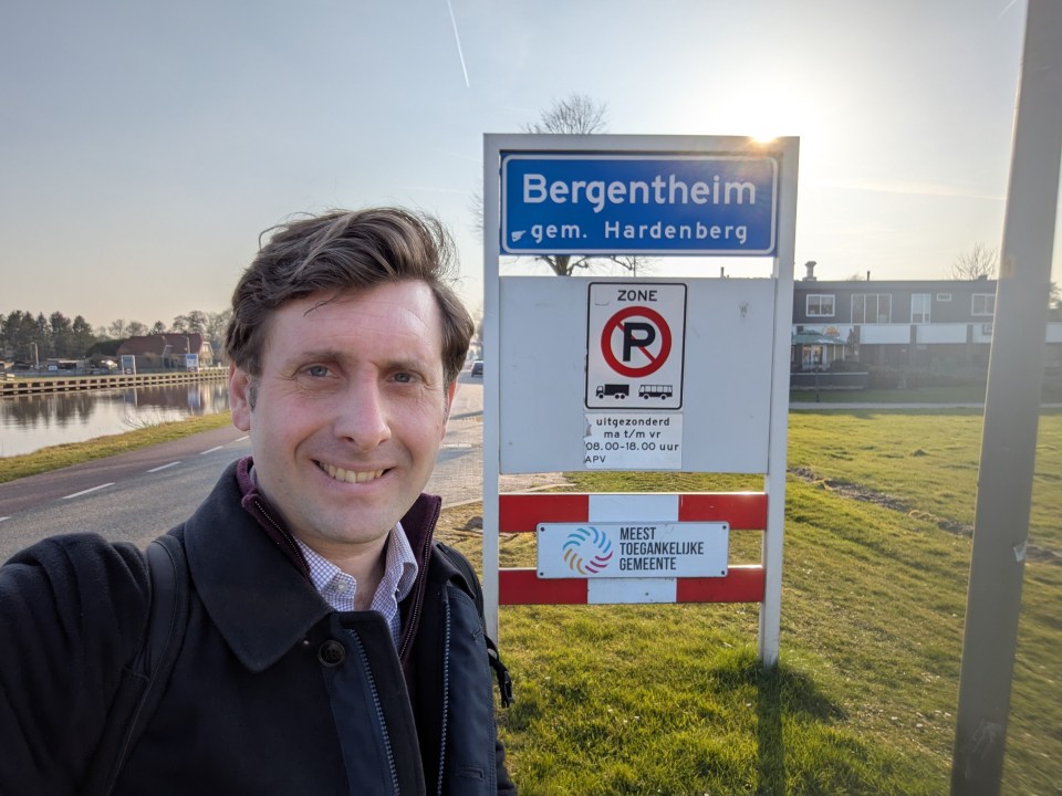 A man stands in front of a Bergentheim, Netherlands sign.