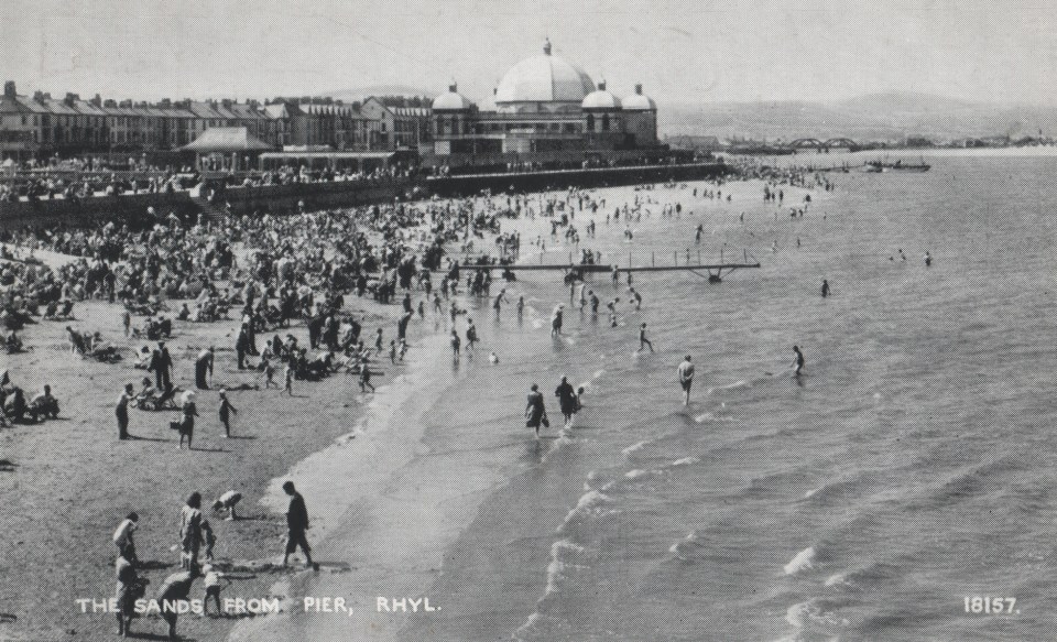 Vintage postcard of Rhyl beach in North Wales showing the promenade, Pavilion, and bathers.