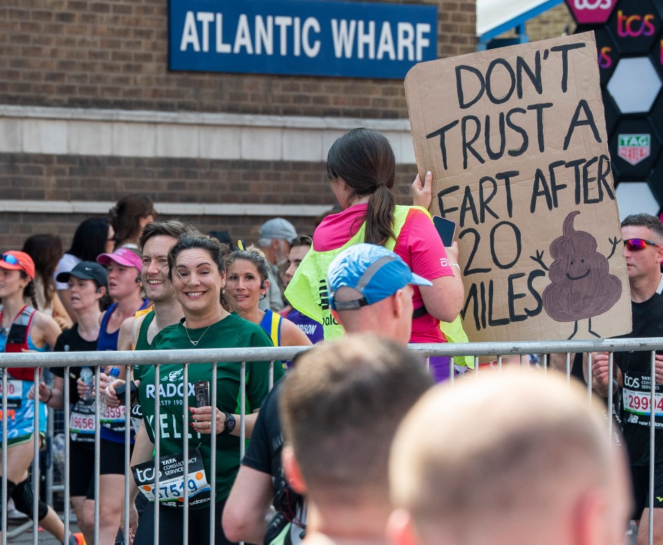 Woman holding sign that says "Don't trust a fart after 20 miles" at a marathon.