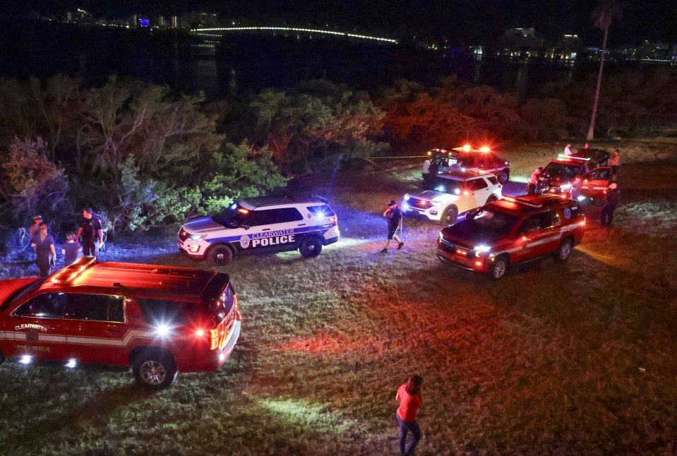 Emergency responders at a beach at night near a boat crash.
