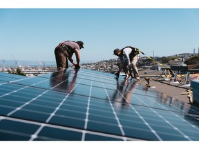 Workers install solar panels on the roof of a home in San Francisco, California. Photographer: Michaela Vatcheva/Bloomberg