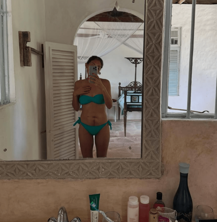 Mirror reflection of a woman in a teal bikini.