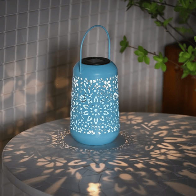 Blue solar-powered lantern with cut-out floral pattern casting shadows.