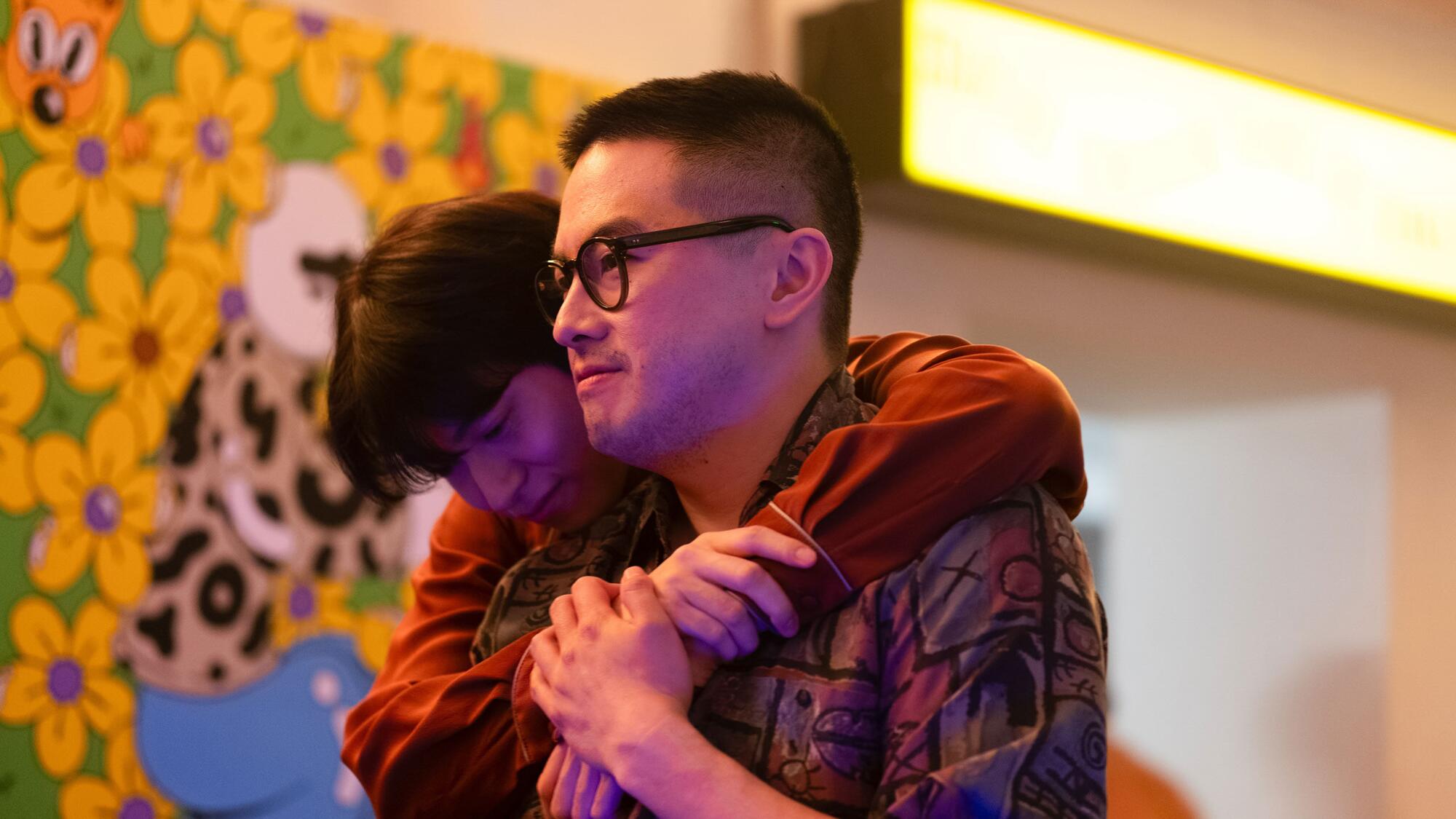 Two men hug.