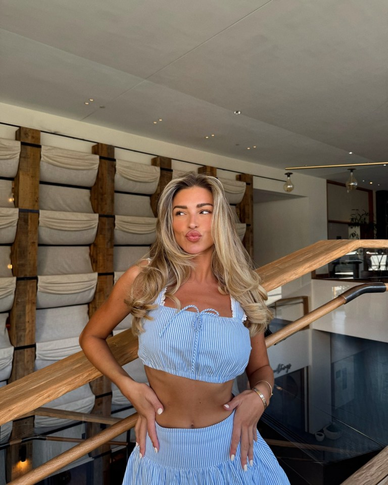 Zara McDermott posing in a blue striped crop top and skirt.