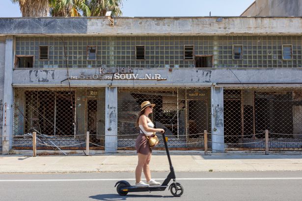 Tourist travelling on scooter through empty streets of Varosha