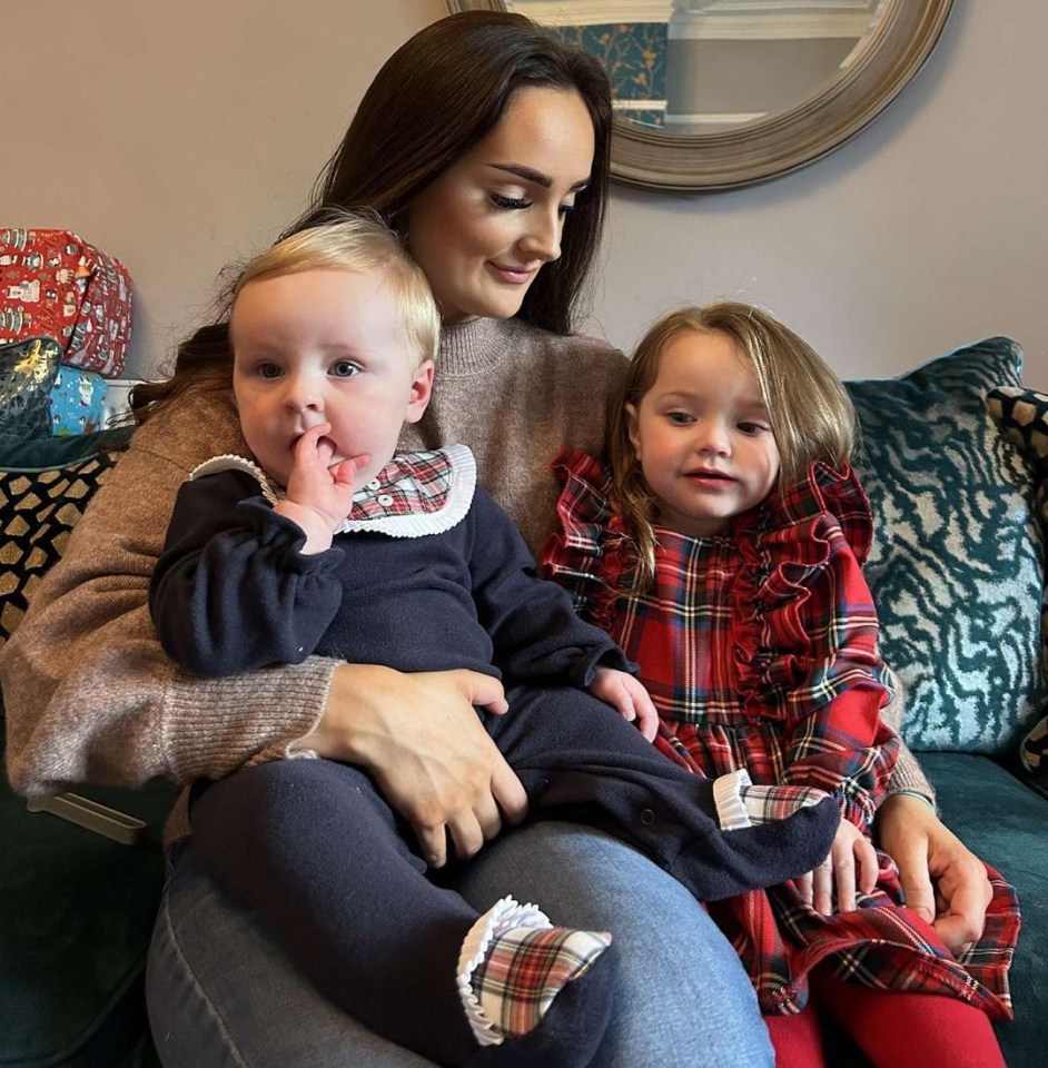 A woman holding two young children.