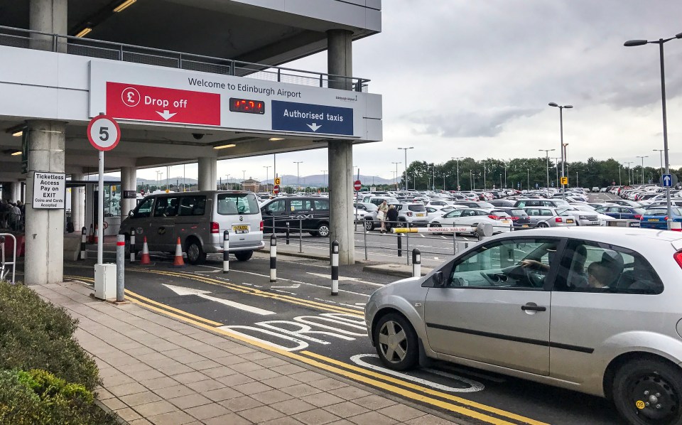 Edinburgh Airport drop-off zone with cars and signage.