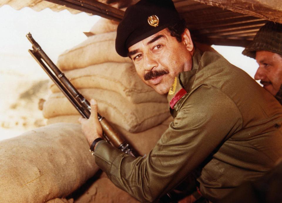 Saddam Hussein holding a rifle.