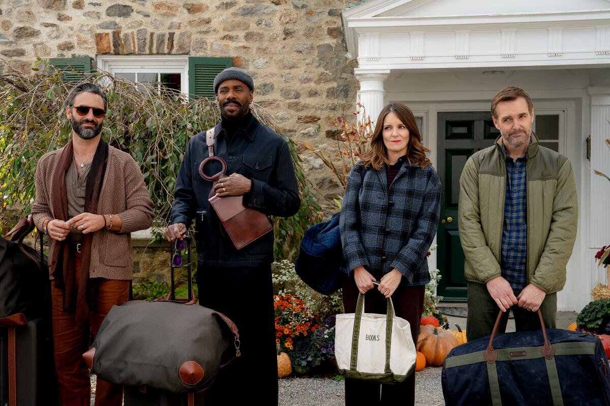 Three men and a woman stand side by side while holding luggage