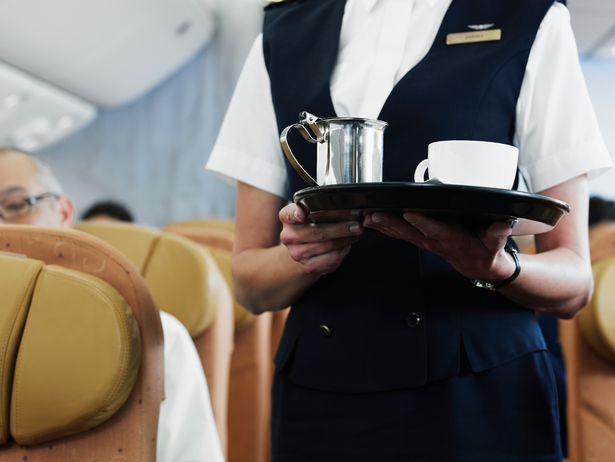 Flight attendant carrying coffee service on plane