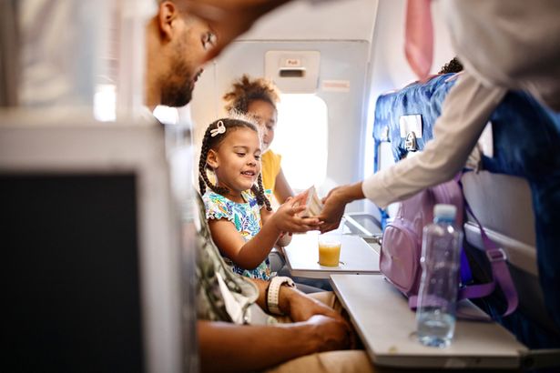 Image of child served food and drink on a plane