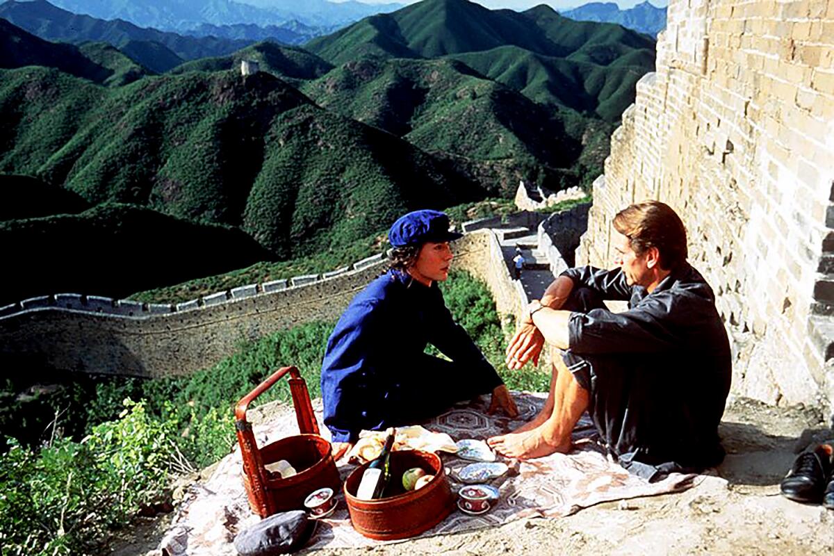 Two people have a picnic on a mountainside.