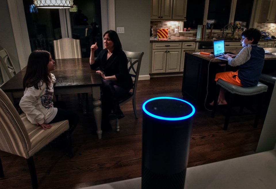 A woman and her two children using an Amazon Alexa device in their home.