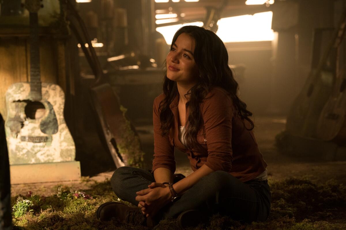 Isabela Merced sitting on the floor near guitars