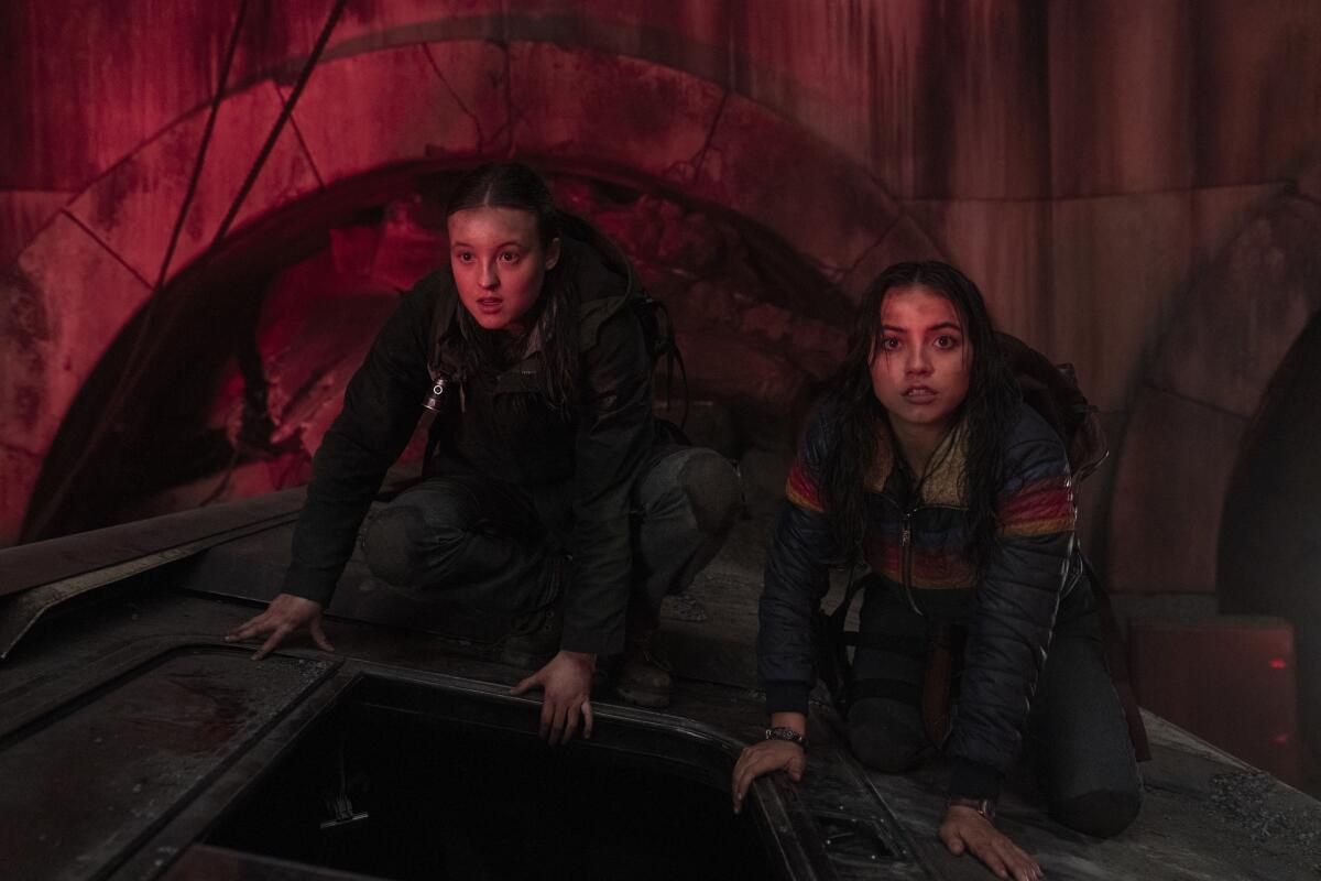 a disheveled Bella Ramsey and Isabela Merced crouched on top of a wrecked subway car