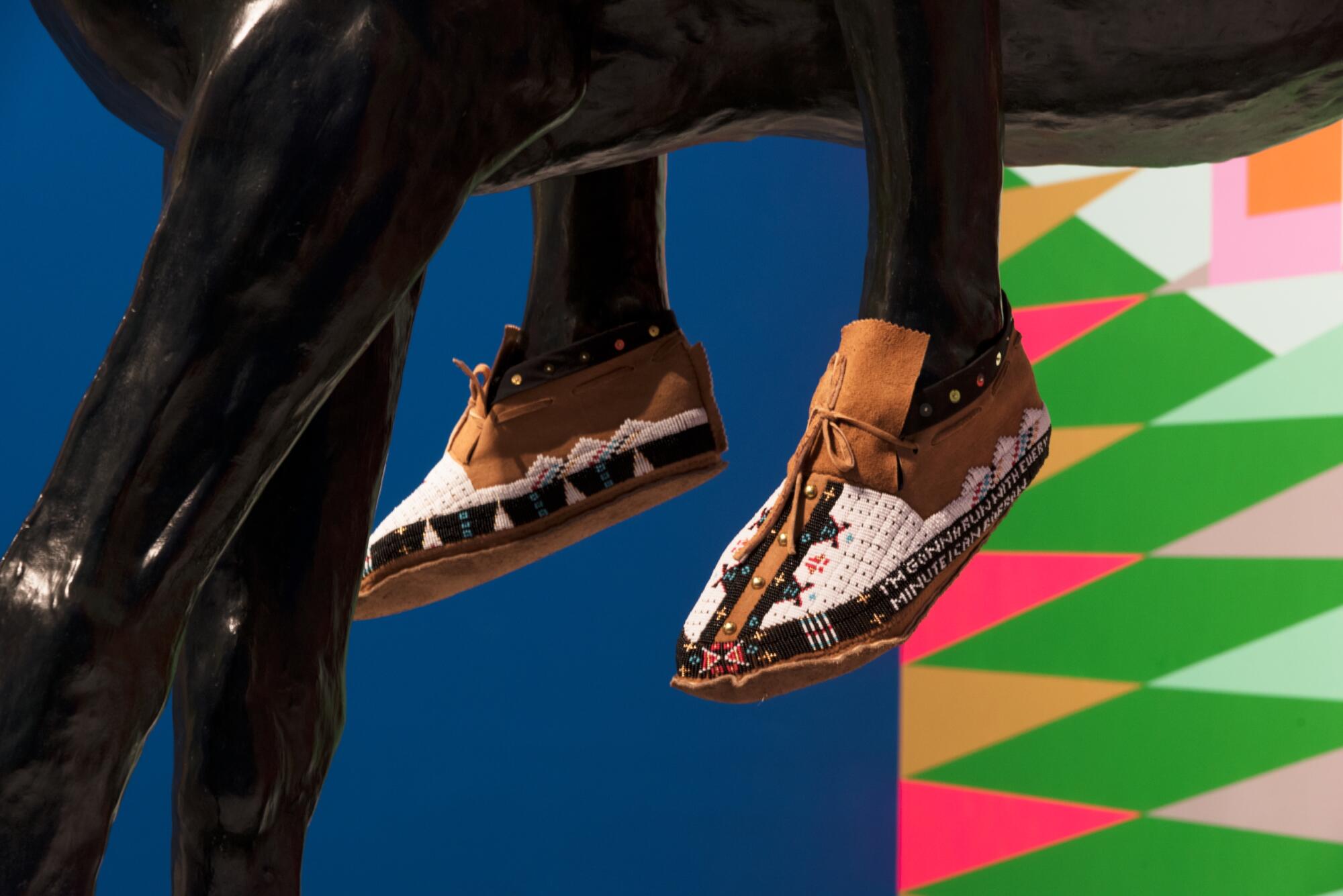 The feet of a bronze statue have been fitted with beaded Native American moccasins.  
