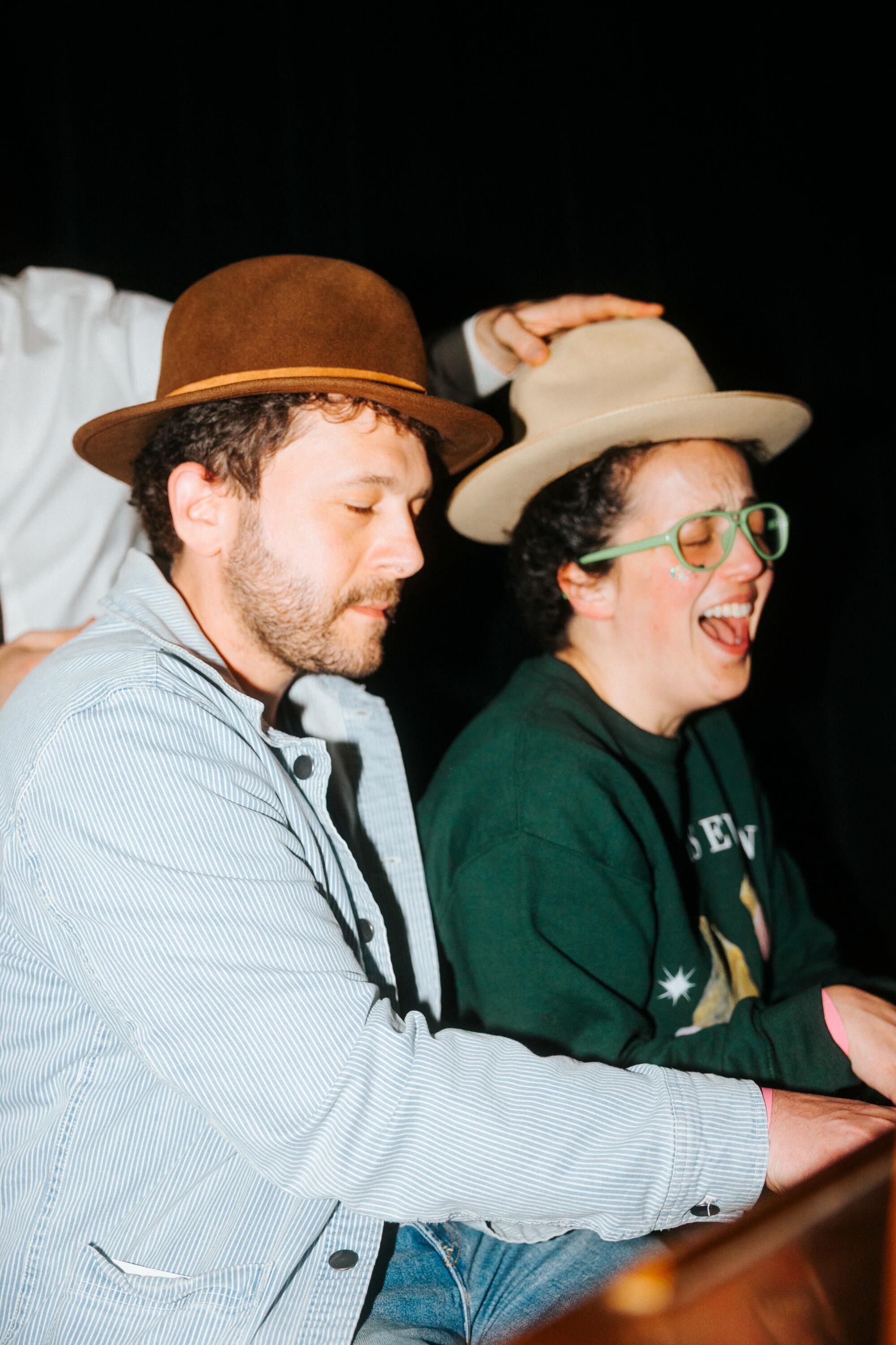 Two people play a piano.