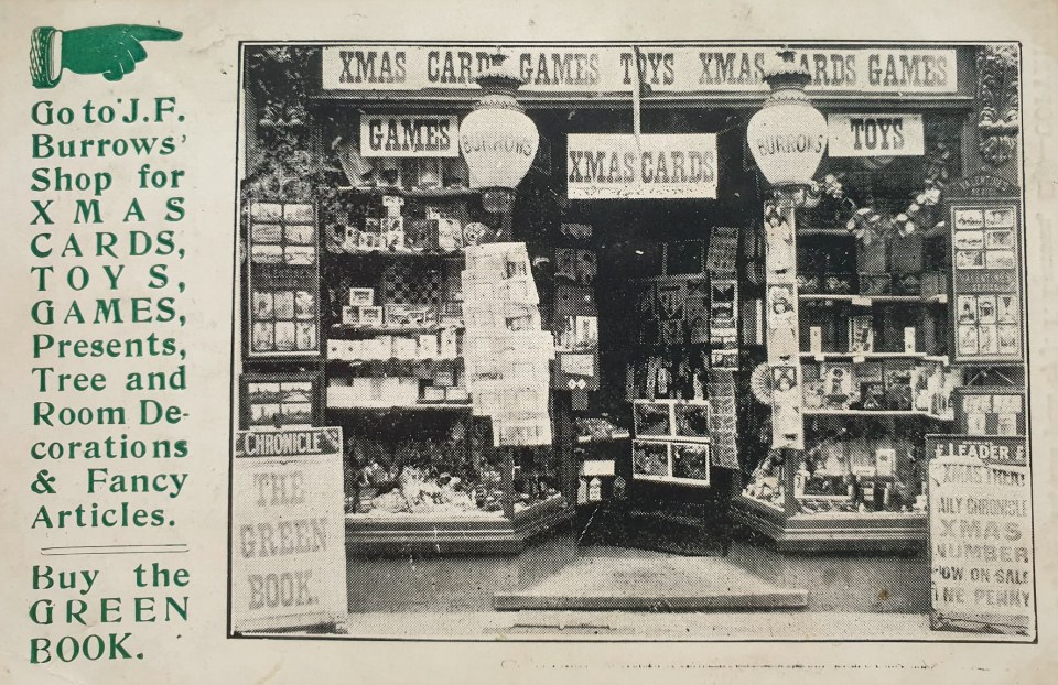 Black and white photo of Burrows' shop window displaying Christmas cards, toys, and games.