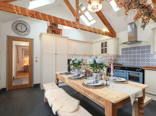 Smart white and blue kitchen with large wooden dining table and benches