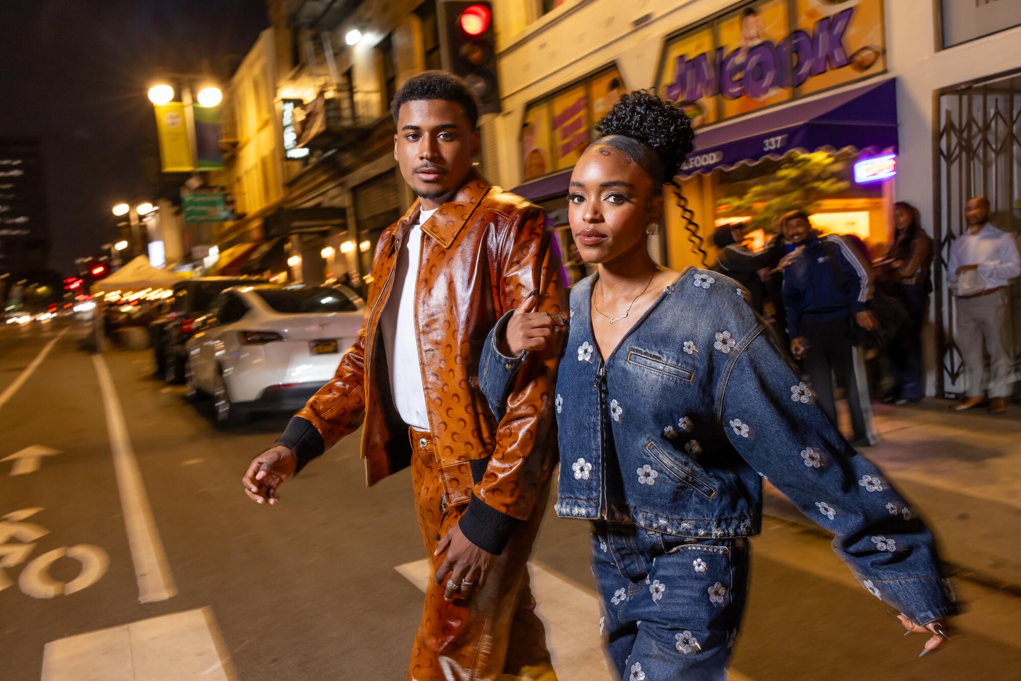 A guy in a matching brown leather ensemble and a woman in a matching jean outfit walk through Little Tokyo