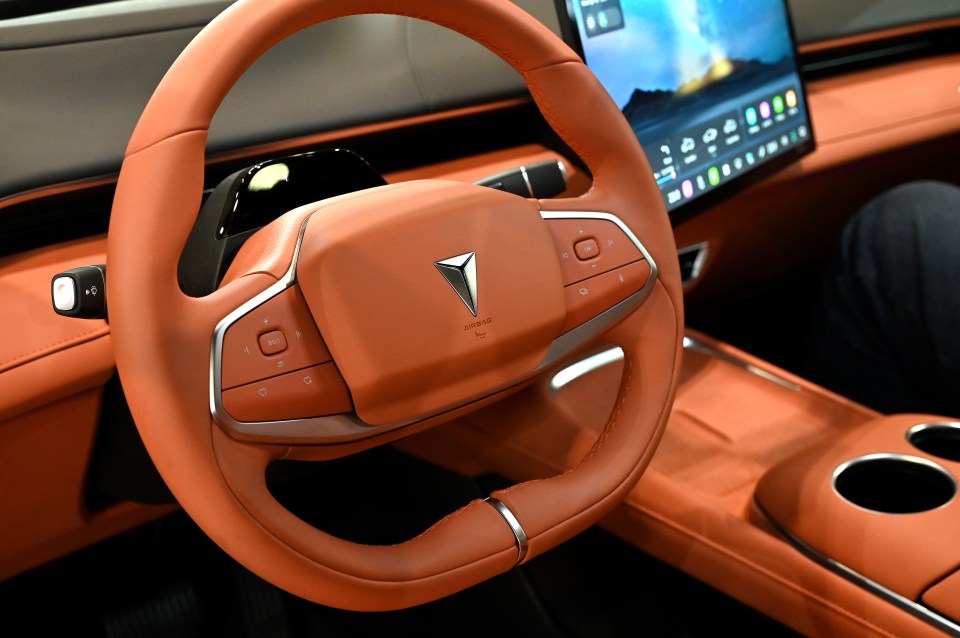 Close-up of an orange leather steering wheel and dashboard of a Changan Deepal S07 all-electric SUV.