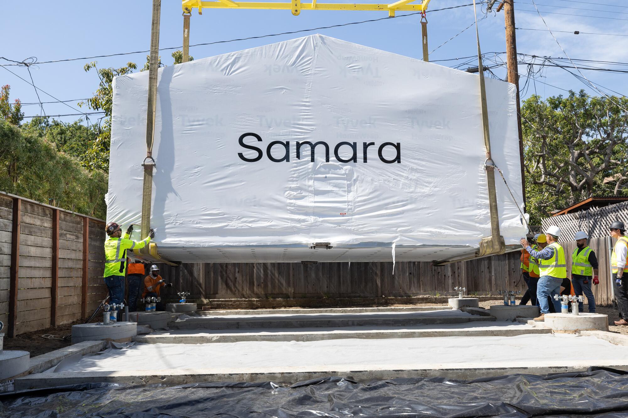 A factory-made Samara house wrapped in plastic is craned onto its foundation at a project site in Culver City in March.