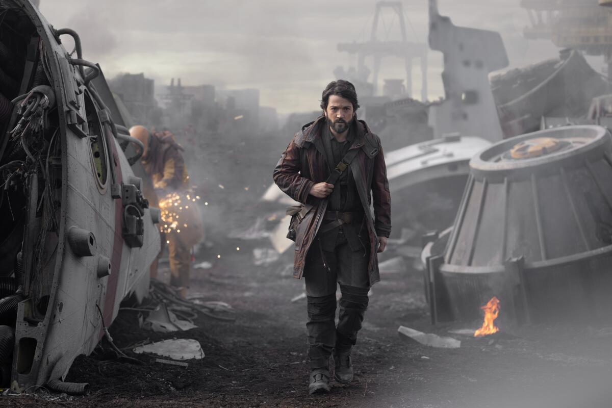 A man wearing a coat walks through wreckage