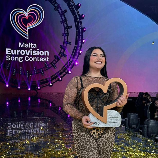 Miriana Conte in a leopard-print outfit holding a trophy on a stage.