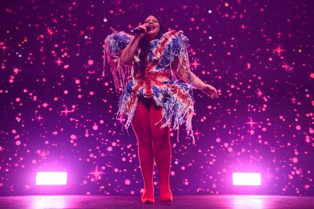 Miriana Conte in a Union Jack top and red leggings holding a microphone whilst performing at London Eurovision Party 2025.