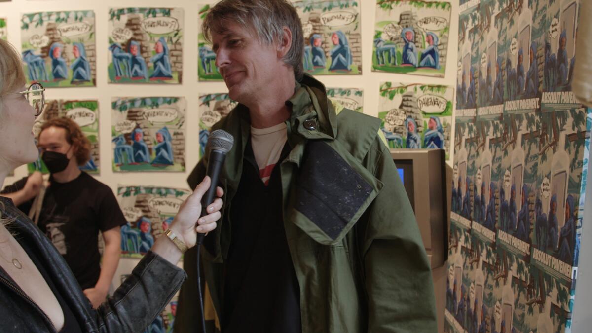 A smiling man gives an interview in an exhibit.