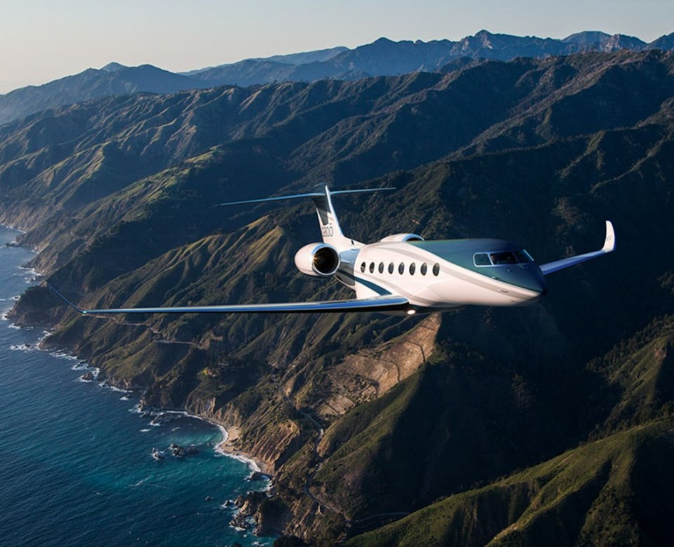 Private jet flying over a coastal mountain range.