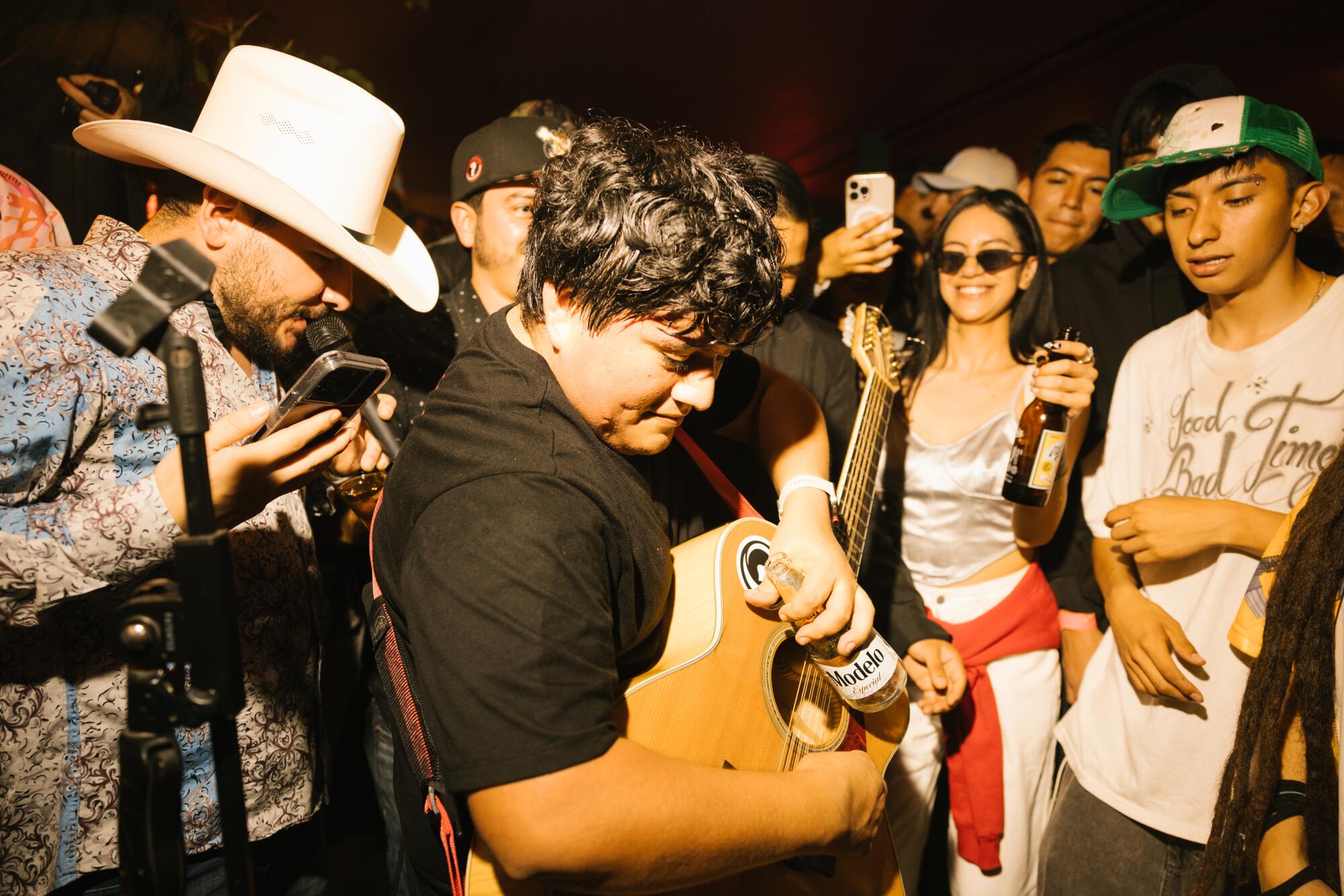 A guitarist plays his guitar with a beer