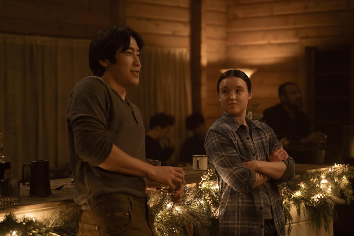 Young Mazino and Bella Ramsey lean against a counter at a party in "The Last of Us"
