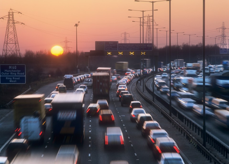 Rush-hour traffic on a multi-lane highway at sunset.