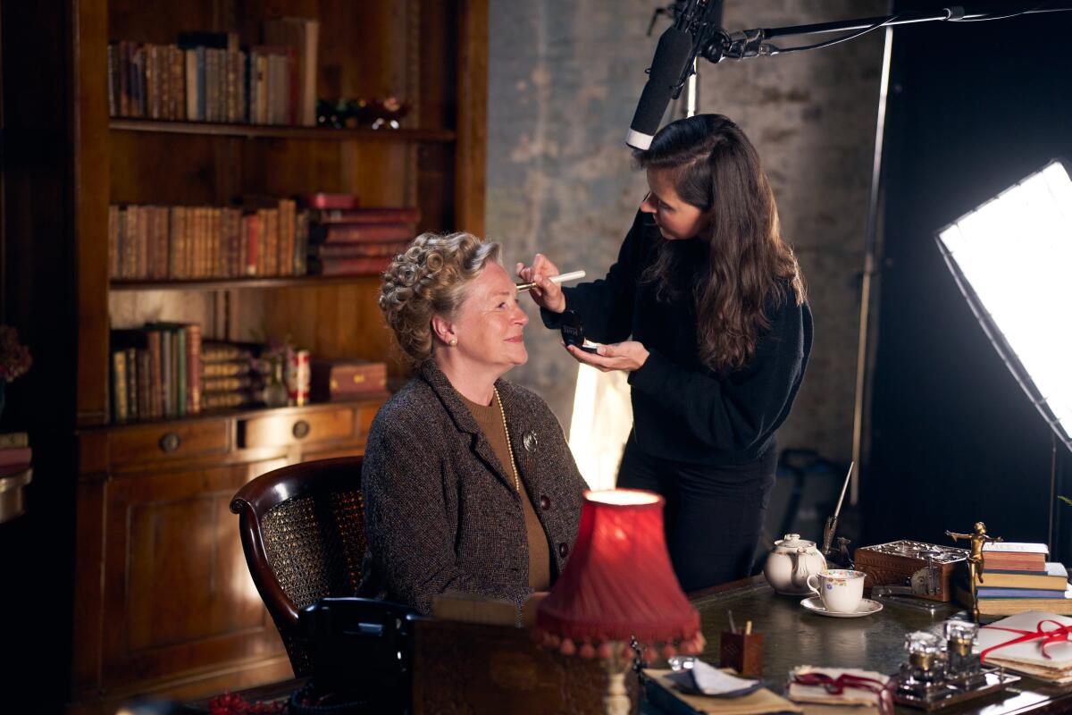 Vivien Keene sits in a chair as a makeup artist applies makeup.