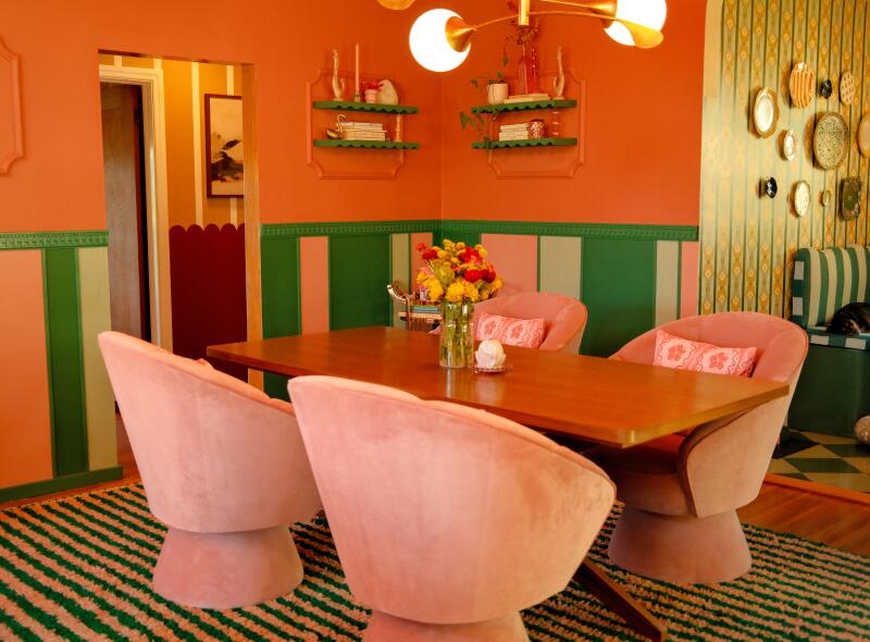 A pink and green and coral dining room with pink velvet chairs