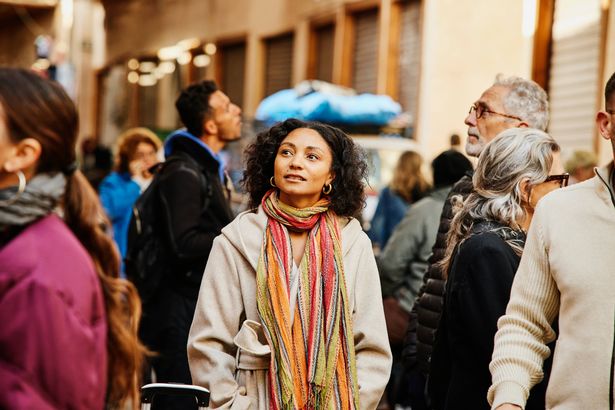Medium shot of solo female traveler admiring the architecture while on walking tour of the medina of Marrakech during vacation in Morocco